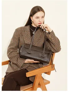 Close-up of a vintage brown leather shoulder bag shown in a classic lifestyle setting