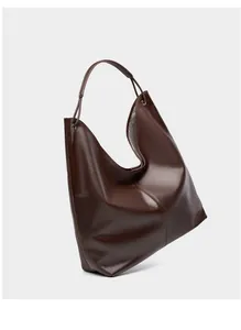 Detalle del bolso tote de cuero marrón oscuro con apertura asimétrica en forma de U