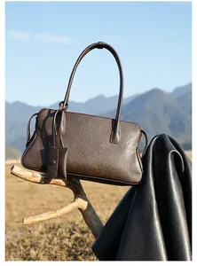 Detalle de bolso tote de cuero marrón oscuro con pequeño colgante en el asa