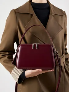 Minimalist burgundy leather square handbag with dual zippers for crossbody and hand carry
