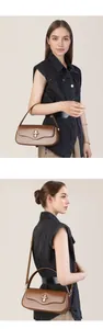 Macro view of a brown leather baguette bag featuring a gold metal buckle and shoulder strap