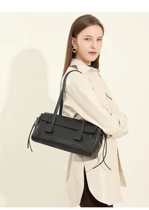 Profile view of black leather shoulder bag with side tassel detail on female model