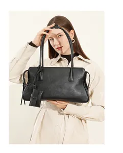 Detalle de bolso tote de cuero negro con pequeño monedero y correas largas de hombro