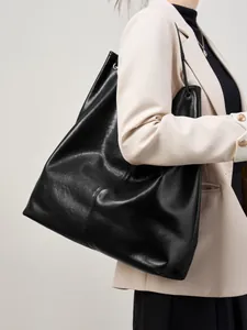 Bolso tote grande de cuero negro para mujer llevado por una modelo en estilo oficina