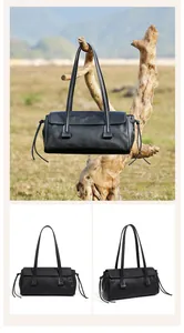 Detailed view of a black leather shoulder bag with side drawstring details and long strap