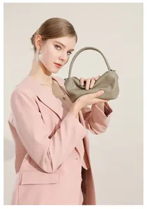 Dettaglio della borsa in pelle verde salvia tenuta da modella in giacca rosa