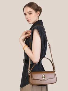 Brown leather baguette underarm bag with gold metal buckle shown on model in side view
