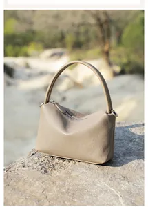 Dettaglio di borsa a mano minimalista in pelle talpa posta su roccia naturale nel bosco