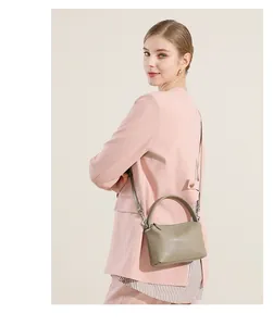 Dettaglio di una borsa a tracolla in pelle verde oliva indossata con un blazer rosa
