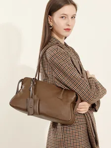 Bolso tote grande de cuero auténtico marrón vintage llevado por modelo con traje de cuadros
