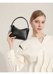 Dettaglio borsa a mano minimalista in pelle nera con manico curvo e design raffinato