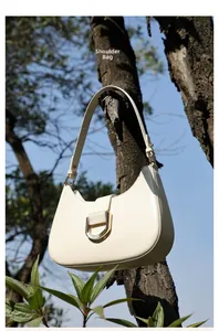 Detail der cremefarbenen Leder-Achseltasche mit silberner D-Schnalle am Baumzweig