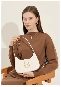 Modell mit schicker beiger Hobo-Tasche aus Leder mit goldenen Details und braunem Strick