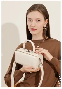 Detail view of cream leather box bag showing silver metal clasp and adjustable wide strap
