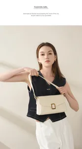 Chic cream leather shoulder bag featuring a prominent gold rectangular metal clasp