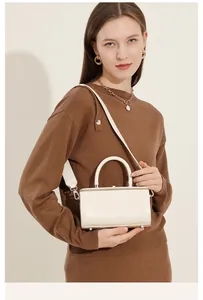 Detailed view of cream leather box bag with silver hardware and adjustable straps