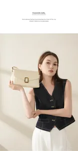 Close-up of cream leather handbag featuring a prominent gold rectangular metal buckle