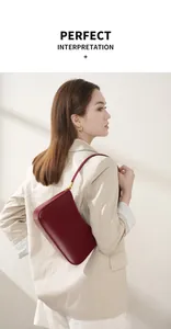 Minimalist burgundy leather baguette shoulder bag detail worn with a beige blazer