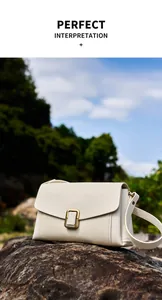 Macro shot of cream leather shoulder bag with vintage gold buckle on a natural rock surface
