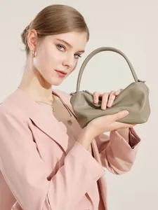 Borsa a mano cloud in pelle arricciata verde oliva con manici sottili indossata da modella