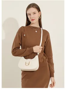 Schicke beige Leder-Baguette-Tasche mit Horsebit-Schnalle an Model in Strickmode