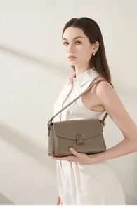 Chic khaki veg-tanned leather shoulder bag with gold square buckle shown on model