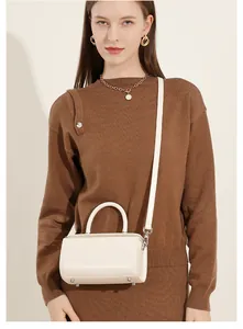 Detail view of cream white leather box bag featuring metal base studs and adjustable strap