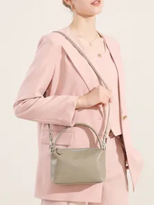 Borsa a mano minimalista in pelle bovina verde salvia con tracolla su modella in blazer