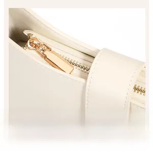 Detailansicht des goldenen Vintage-Reißverschlusses an einer cremefarbenen Ledertasche