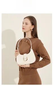 Cremeweiße Leder-Baguette-Tasche, getragen von einem Model im Strickoutfit