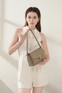 Detail of grey pebbled leather shoulder bag featuring a gold square metallic lock clasp