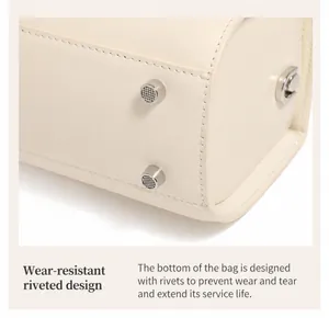 Detail view of cream leather handbag base featuring four silver protective metal rivets