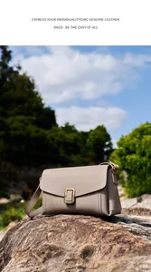 Detailed close-up of taupe genuine leather crossbody bag with vintage gold buckle on a rock