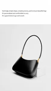 Close-up of black leather underarm bag with gold metal buckles on minimalist white stand