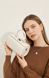 Detail of a beige leather box handbag with silver twist lock and round top handle