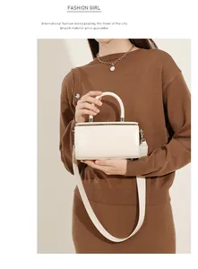 Detail of cream leather box bag worn with a brown sweater for a chic shoulder look
