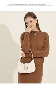 Detail einer cremeweißen Leder-Halbmondtasche mit goldenem D-Ring-Verschluss an einem Model
