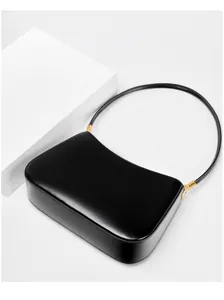 Macro detail of minimalist black leather underarm bag with elegant gold metal buckle