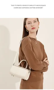 Close-up of white leather cylinder bag with a handle and detachable shoulder strap