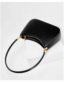 Top view of minimalist black leather half-moon shoulder bag with sleek gold-tone hardware
