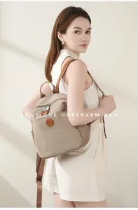 Detail of beige oxford fabric backpack with premium brown leather trim and round logo