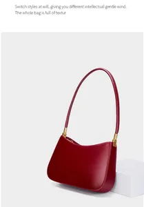 Detailed close-up of dark red leather shoulder bag with polished gold metal hardware