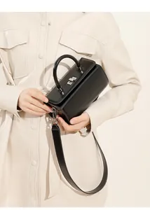 Detail of black leather cylinder box bag with silver metal lock and top handle