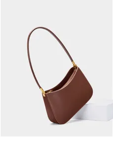 Detail view of smooth dark brown leather texture and golden zipper hardware on shoulder bag