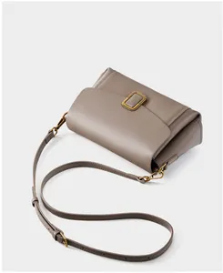 Macro detail of taupe leather bag with vintage gold square buckle and adjustable strap