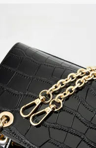 Détail du sac en cuir croco noir avec bandoulière en chaîne dorée en acier titane