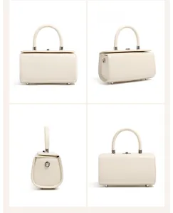Detail view of cream leather box bag showing silver hardware and metal bottom studs