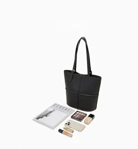 Top-down view of black pebbled leather tote bag filled with cosmetics and a magazine