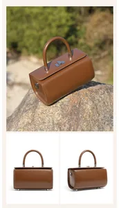 Detail of dark brown leather box bag with silver twist lock and sturdy top handle