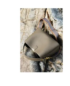 Dettaglio della borsa in pelle taupe con finiture dorate su uno sfondo di roccia naturale
